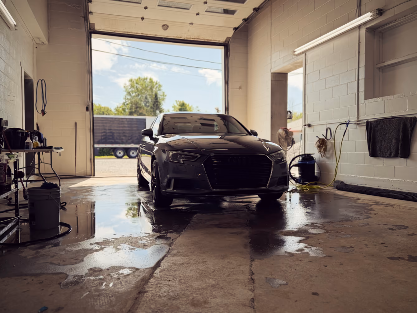 Véhicule fraîchement lavé dans l'atelier de K.L.G, porte de garage ouverte sur la lumière du jour
